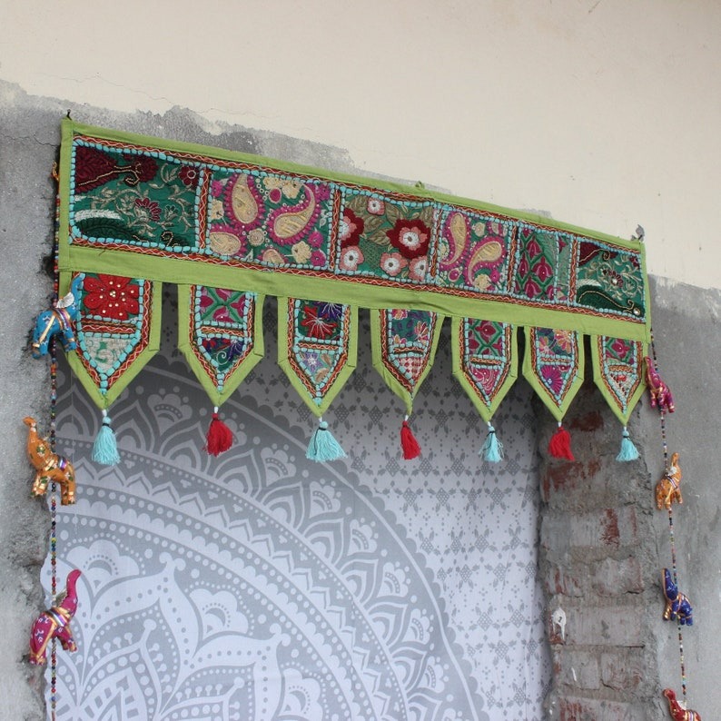 Handmade boho valance with colorful embroidered patchwork and hanging tassels used as a decorative door topper or window border